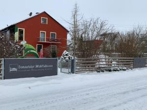 una casa rossa con un cartello nella neve di Donautaler Wohlfühloase a Gundelfingen