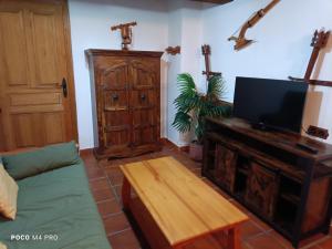 sala de estar con TV, sofá y mesa en Viejo Horno en Torreiglesias