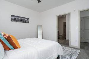 Dormitorio blanco con cama blanca y almohadas de color naranja en Luxurious One Bedroom Whitestown, en Whitestown