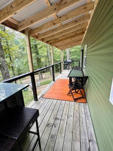 une terrasse couverte avec une table et des chaises sur une terrasse en bois dans l'établissement Red River Gorge Couples and Climbing getaway in Prime Location!, à Campton