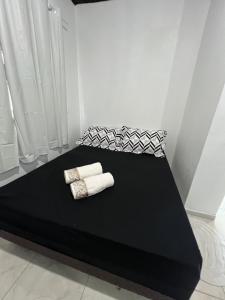 Una cama negra con dos toallas blancas. en Suite 1- black em Praia bonita hospedagem, en São Francisco do Sul