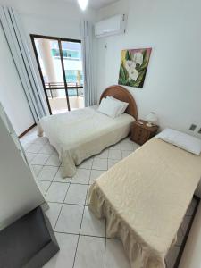 two beds in a room with a window at Apartamento 200 metros da praia 03 quartos com ar condicionado - Meia Praia - Itapema in Itapema