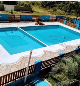 una gran piscina azul junto a una valla en Pousada Luzemar flat, en São Francisco do Sul