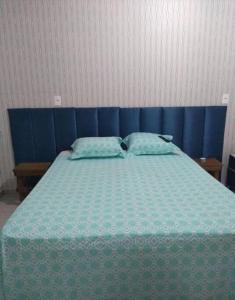 1 dormitorio con 1 cama azul y 2 almohadas en Pousada Luzemar flat, en São Francisco do Sul