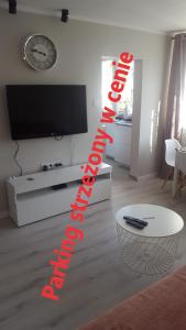 a living room with a flat screen tv and a table at PAW Apartament. Rodzinny, super apartament. in Koszalin