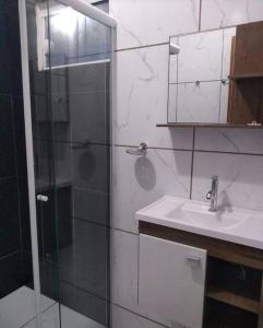 y baño con ducha acristalada y lavamanos. en Pousada Luzemar flat, en São Francisco do Sul