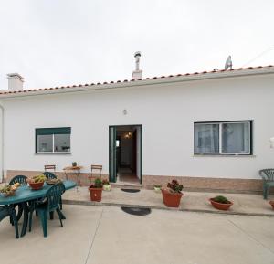 a white building with a patio with tables and chairs at Casas com Amoras in Serra da Pescaria in Famalicão