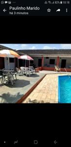 una imagen de un patio con piscina, mesas y sombrillas en Pousada Por do Sol, en Cananéia