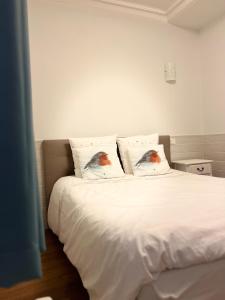 een slaapkamer met een wit bed met 2 kussens bij L'Harmony in Saint-Arnoult-en-Yvelines