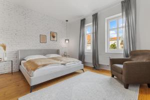 a white bedroom with a bed and a chair at AH Luxury Old Town in Bratislava