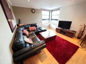 uma sala de estar com um sofá de couro e um tapete vermelho em Lovely Two-bed Apt em Aberdeen