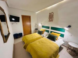 1 dormitorio con 2 camas con sábanas amarillas y TV en Manuel Becerra - Plaza de toros Ventas - ALQUILER TEMPORAL - HOSPITALES, en Madrid