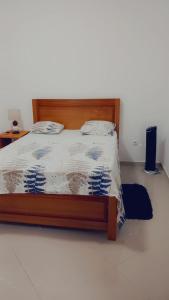 a bed with a wooden frame in a room at Casa Kyara Apart T2 in Praia