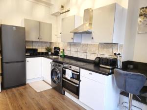 La cuisine est équipée de placards blancs et d'un lave-vaisselle. dans l'établissement Charming flat in Stokes Croft, à Bristol
