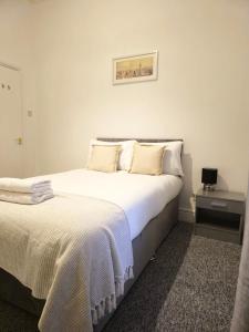 a bedroom with a large white bed and a night stand at Charming flat in Stokes Croft in Bristol