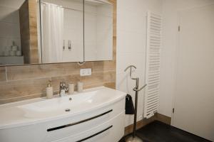 DoreyHome I Luxus - Stylish - Modern House I Parking I Smart TV I Netflix WLAN في باساو: حمام مع حوض أبيض ومرآة