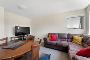 a living room with a couch and a table at T Bar on Twynam - Modern 2BR Apartment l WiFi l Netflix l BBQ l Smart TV l Air-Con in Jindabyne