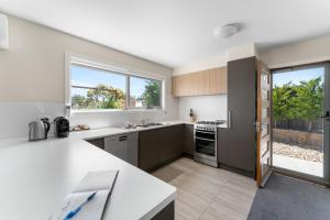 una cucina con banconi bianchi e una grande finestra di T Bar on Twynam - Modern 2BR Apartment l WiFi l Netflix l BBQ l Smart TV l Air-Con a Jindabyne