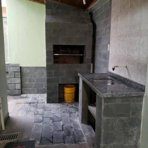 cocina de piedra con fregadero y chimenea en Casa 50m do mar, en Matinhos