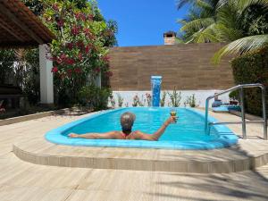 um homem numa piscina com um copo de vinho em Casa Paraiso de Sonho Verde em Paripueira