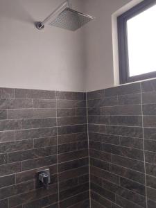 baño con paredes de azulejos marrones y ventana en Arenal Vistas del Paraiso en Nuevo Arenal