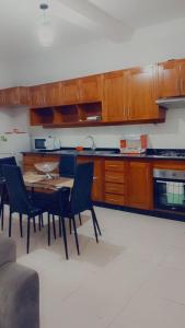 - une cuisine avec des placards en bois, une table et des chaises dans l'établissement Casa Kyara Apart T2, à Praia
