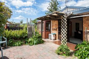 a garden with a brick house with a patio at Denby Crest in Whangarei