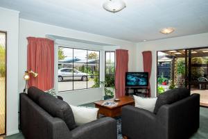 a living room with two chairs and a television at Denby Crest in Whangarei