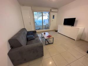 Una sala de estar con un sofá y un televisor de pantalla plana. en Studio Bellepierre, en Saint-Denis