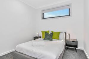 une chambre avec un lit avec des oreillers verts et une fenêtre dans l'établissement The Art of Zen - Modern Comfort between Beach and CBD, à Adélaïde