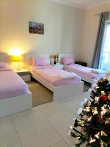 a room with three beds and a christmas tree at Amazing apartment 2 bed rooms in Tecom 6 pax in Dubai