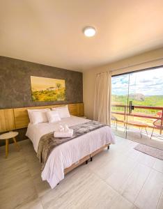 a bedroom with a bed and a large window at Entre Serras Gastropub e Chalés in Monte das Gameleiras