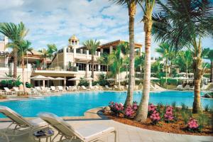 a pool at a resort with palm trees and lounge chairs at The Ritz-Carlton, Sarasota in Sarasota