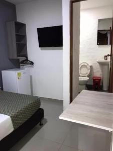 ein Schlafzimmer mit einem Bett und ein Badezimmer mit einem WC in der Unterkunft Hotel Emalú M&C in Quibdó