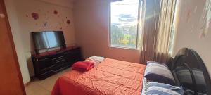 Schlafzimmer mit einem Bett und einem Flachbild-TV in der Unterkunft Apartamento Acogedor in Huancayo