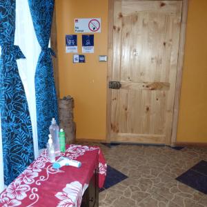una habitación con una mesa con un mantel rojo y una puerta en Cabaña Kaiheke, en Hanga Roa