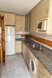 a kitchen with a white refrigerator and a sink at Casa de lujo en la playa frente al campo de golf in El Portil