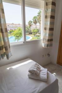 a bed in a room with a window and towels at Casa de lujo en la playa frente al campo de golf in El Portil