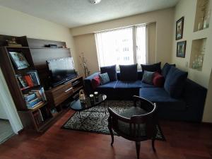 a living room with a blue couch and a tv at Familia Segovia Tejada in Quito