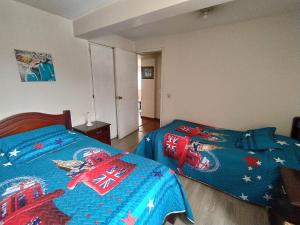 a bedroom with two beds with blue comforters and a bedskirts at Familia Segovia Tejada in Quito