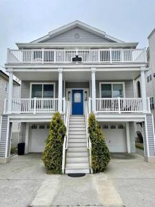 une maison blanche avec une porte bleue et des escaliers dans l'établissement Fabulous 4BR only 1.5 blocks to the beach!, à Wildwood