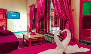 two white swans sitting on a bed in a room at Riad Dar Lalj Fes in Fez