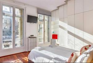 Habitación con cama, TV y ventanas. en Chic Parisian Flat, en París