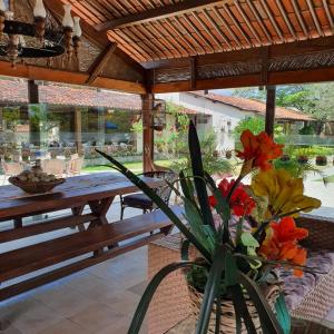 eine Terrasse mit einem Holztisch und einer Vase aus Blumen in der Unterkunft Pousada Fazenda Gloria in Lagoa dos Gatos