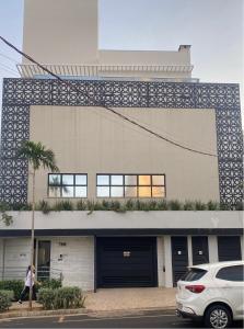 a woman is walking in front of a building at "Flats Uberlândia - FLATS, APARTAMENTOS E QUARTOS in Uberlândia