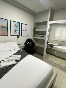 1 dormitorio con 1 cama blanca grande y espejo en Flats Uberlândia en Uberlândia