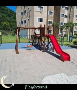 um parque infantil com um escorrega vermelho num parque em Meu Aconchego em Mangaratiba