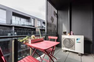 una mesa roja y sillas en el balcón en City-edge Living in Trendy North Melbourne en Melbourne