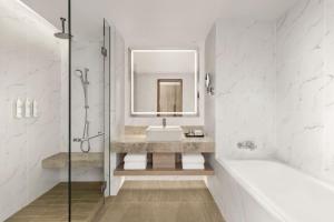 a bathroom with a tub and a sink and a mirror at Putrajaya Marriott Hotel in Putrajaya