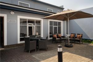 a patio with a table and chairs and an umbrella at Protea Hotel by Marriott Walvis Bay Indongo in Walvis Bay